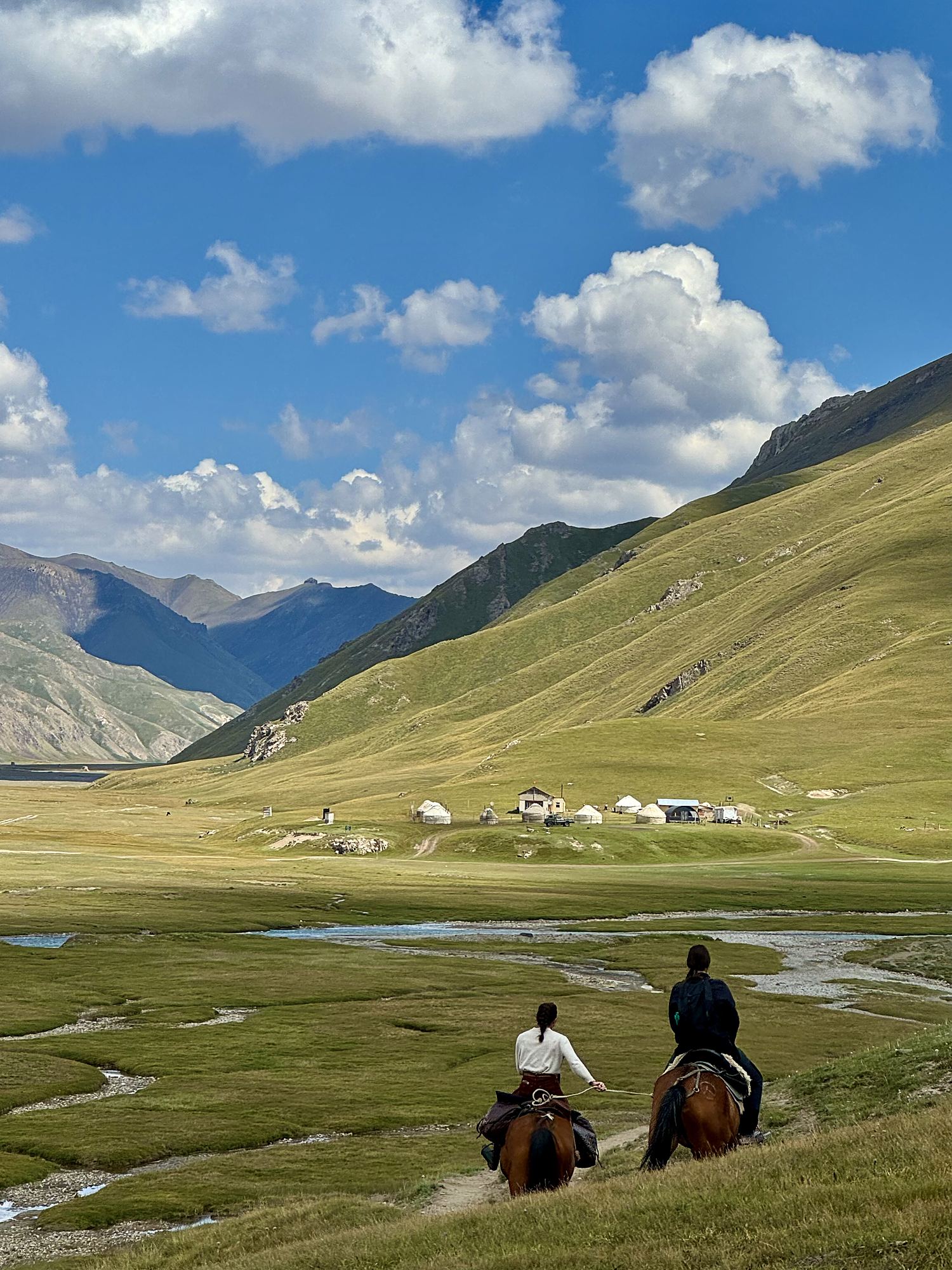Horseback trekking through a Kyrgyz valley toward a yurt camp